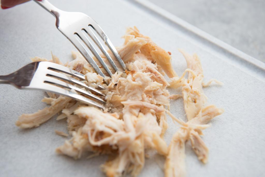 Shredding the chicken with forks.