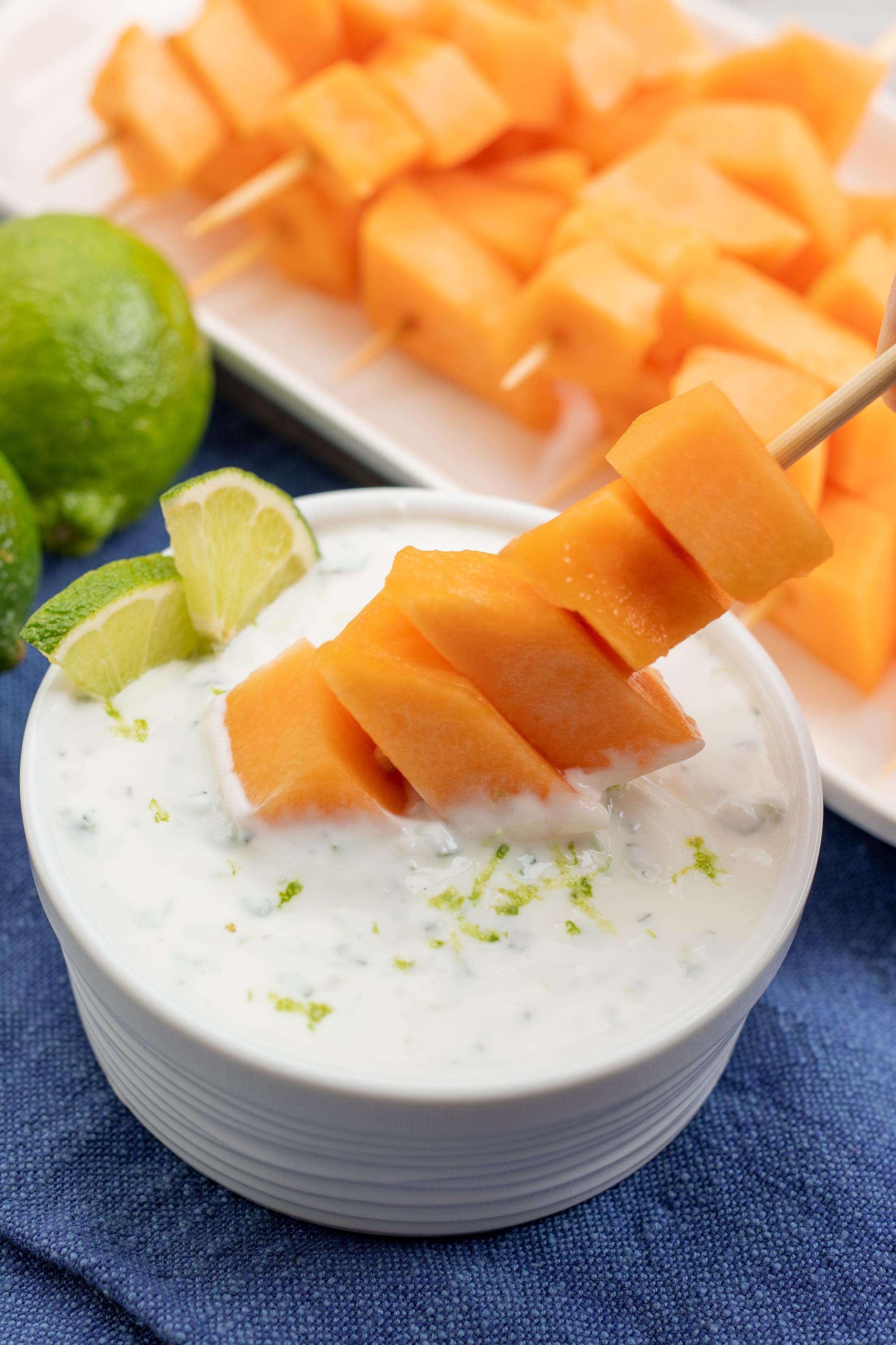 Dipping the cantaloupe skewer in the yogurt sauce.