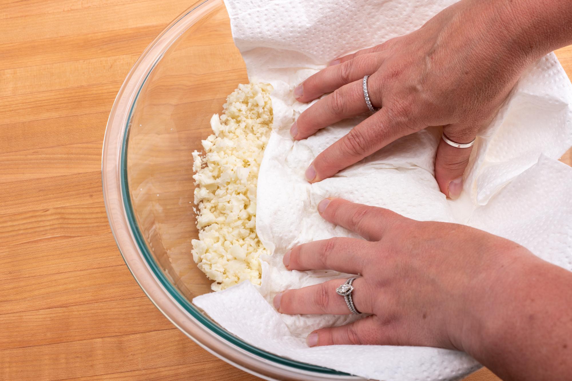 Patting dry the riced cauliflower.