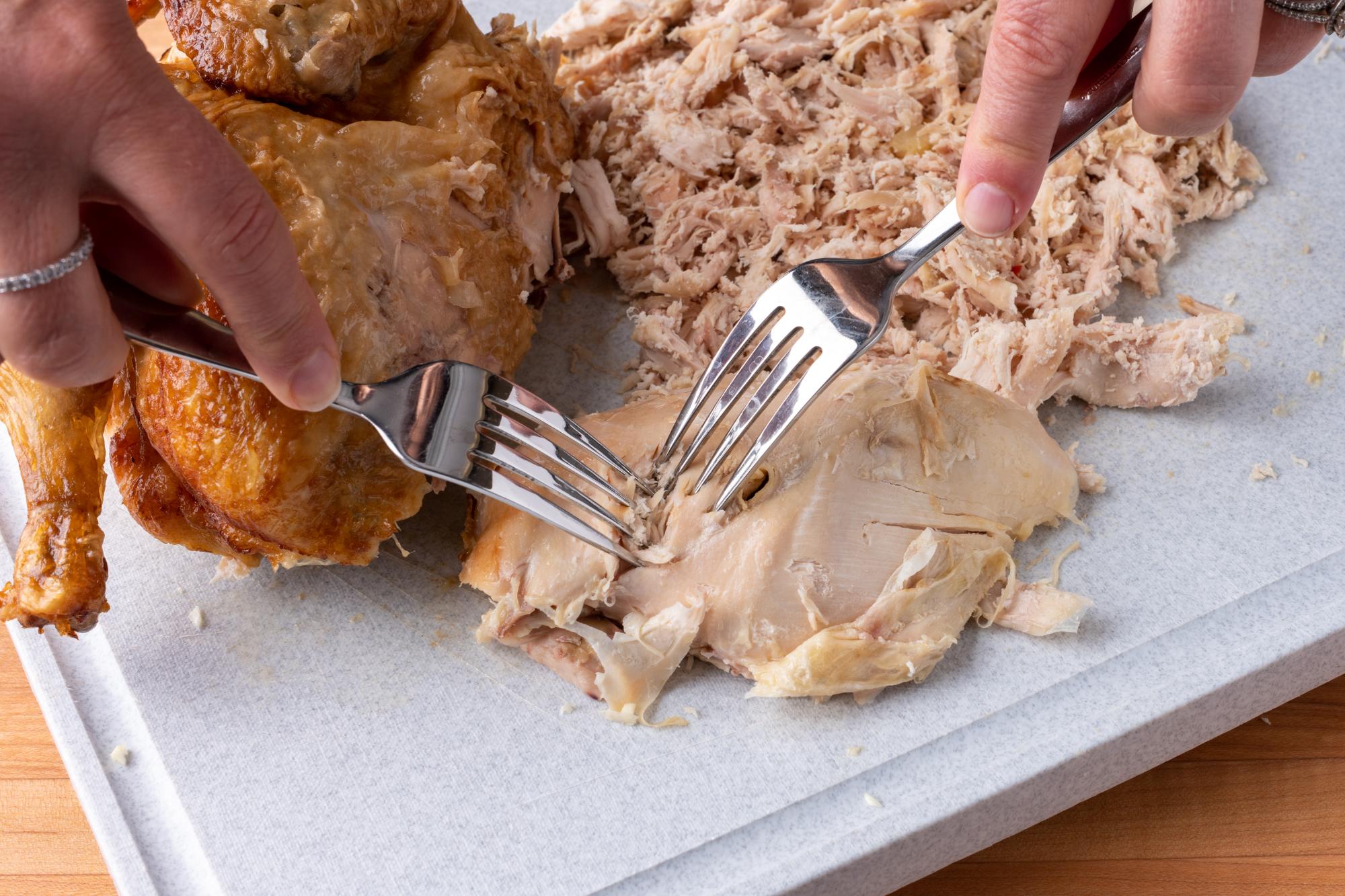 Shredding the chicken with two forks.