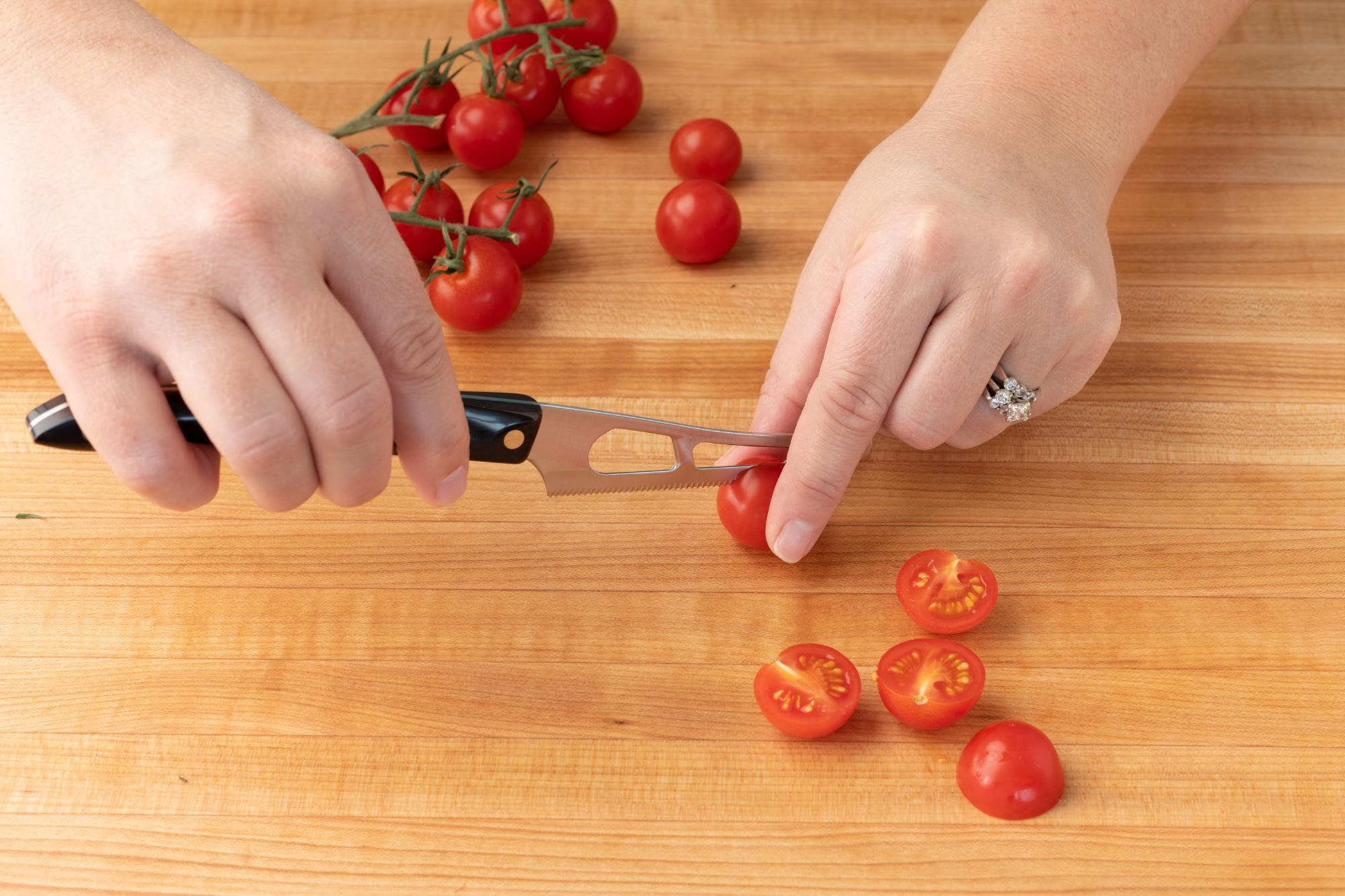 Using the Mini Cheese Knife to slice the tomatoes in half.