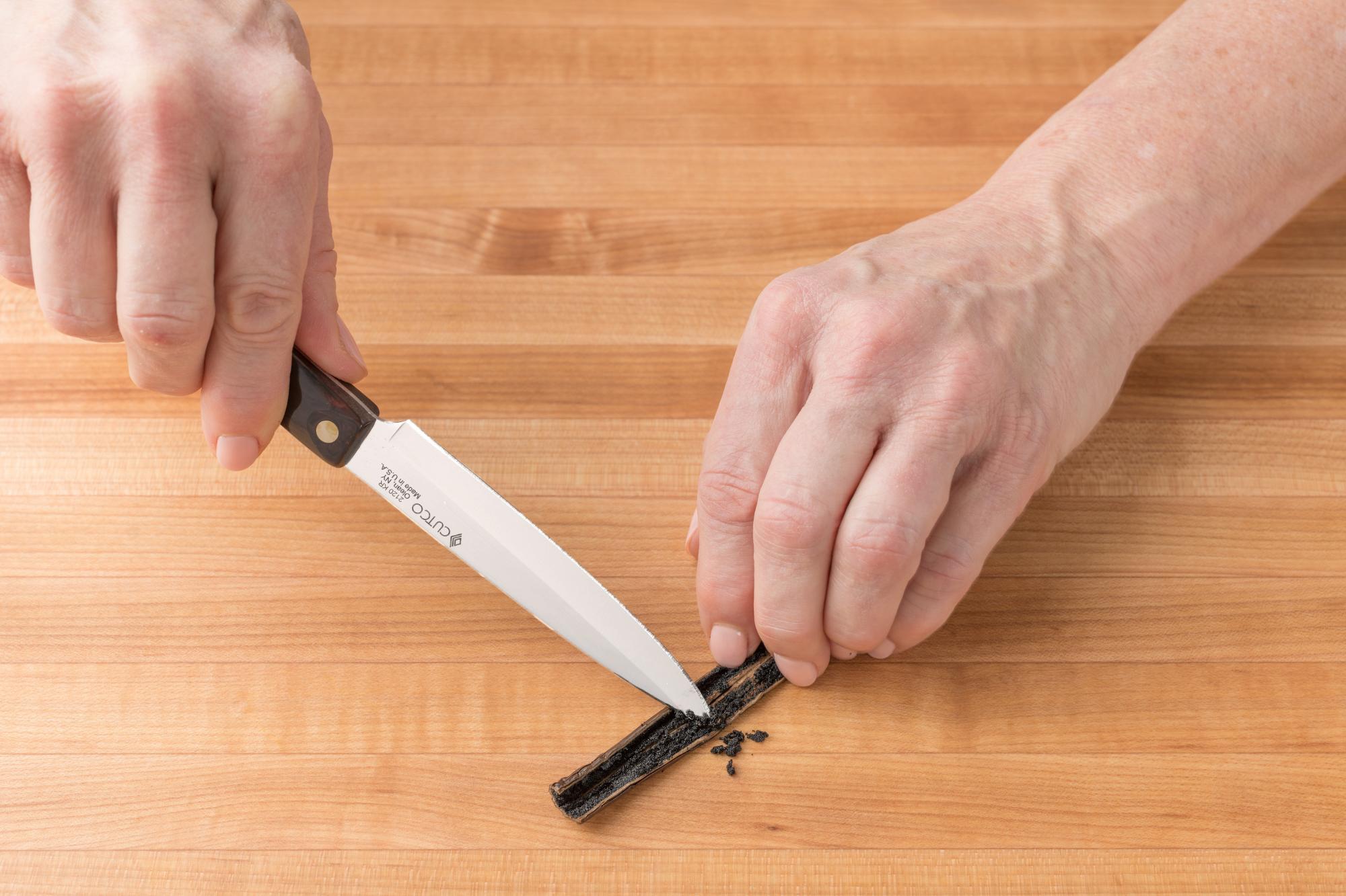 Using the 4 inch paring knife to scrape the vanilla bean.