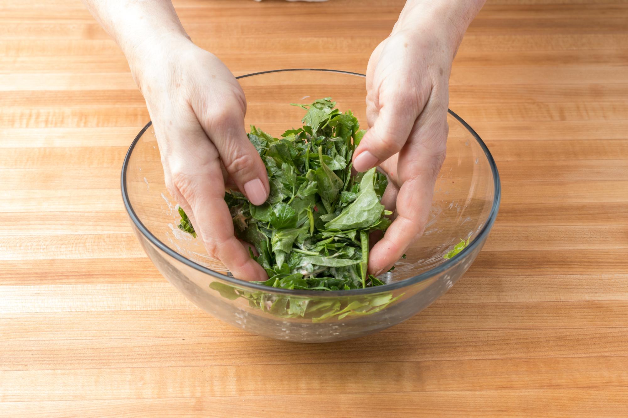 Tossing the sand with your hands to incorporate the dressing.