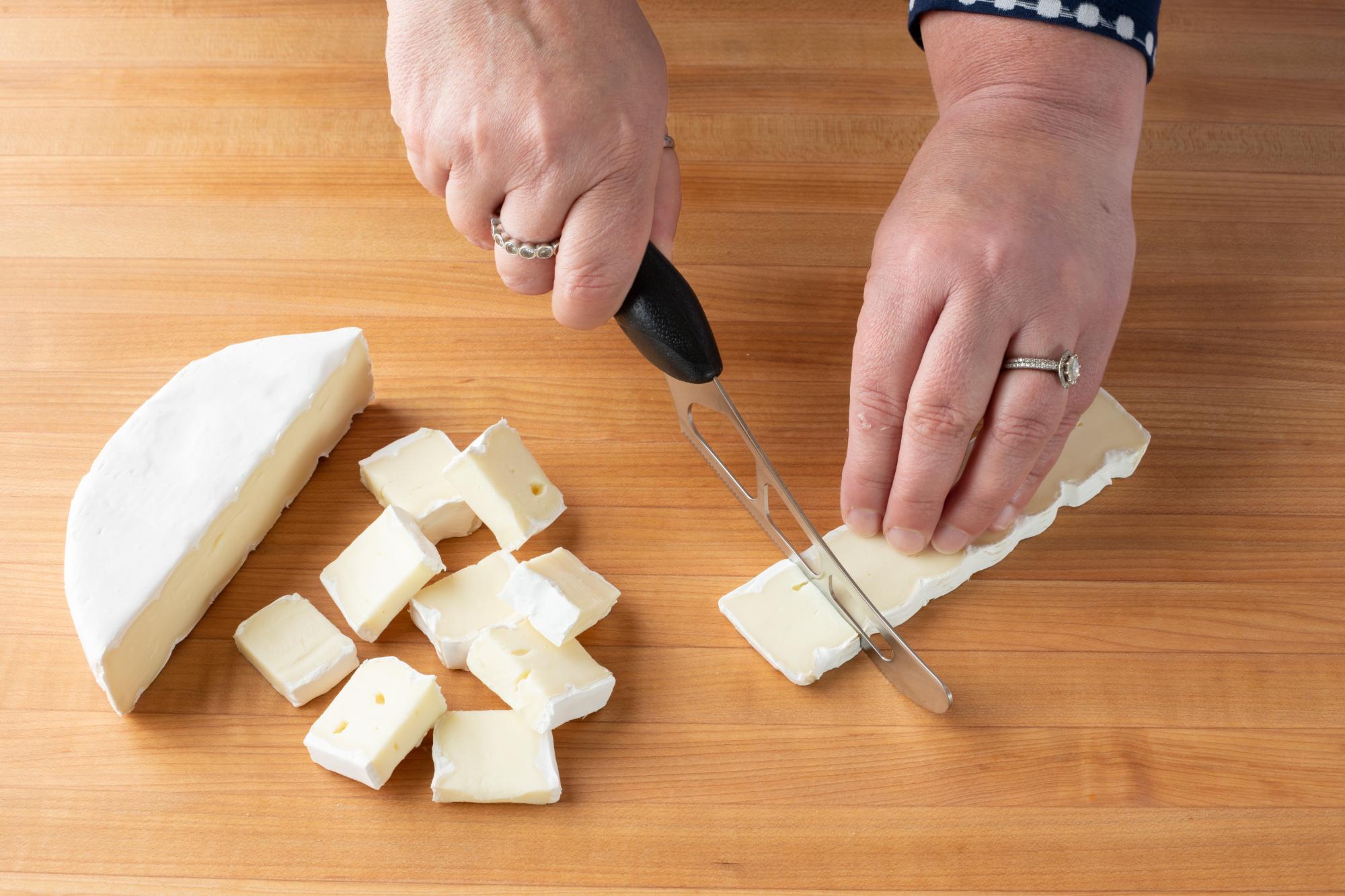Cutting the Brie into small pieces using a Cheese Knife.
