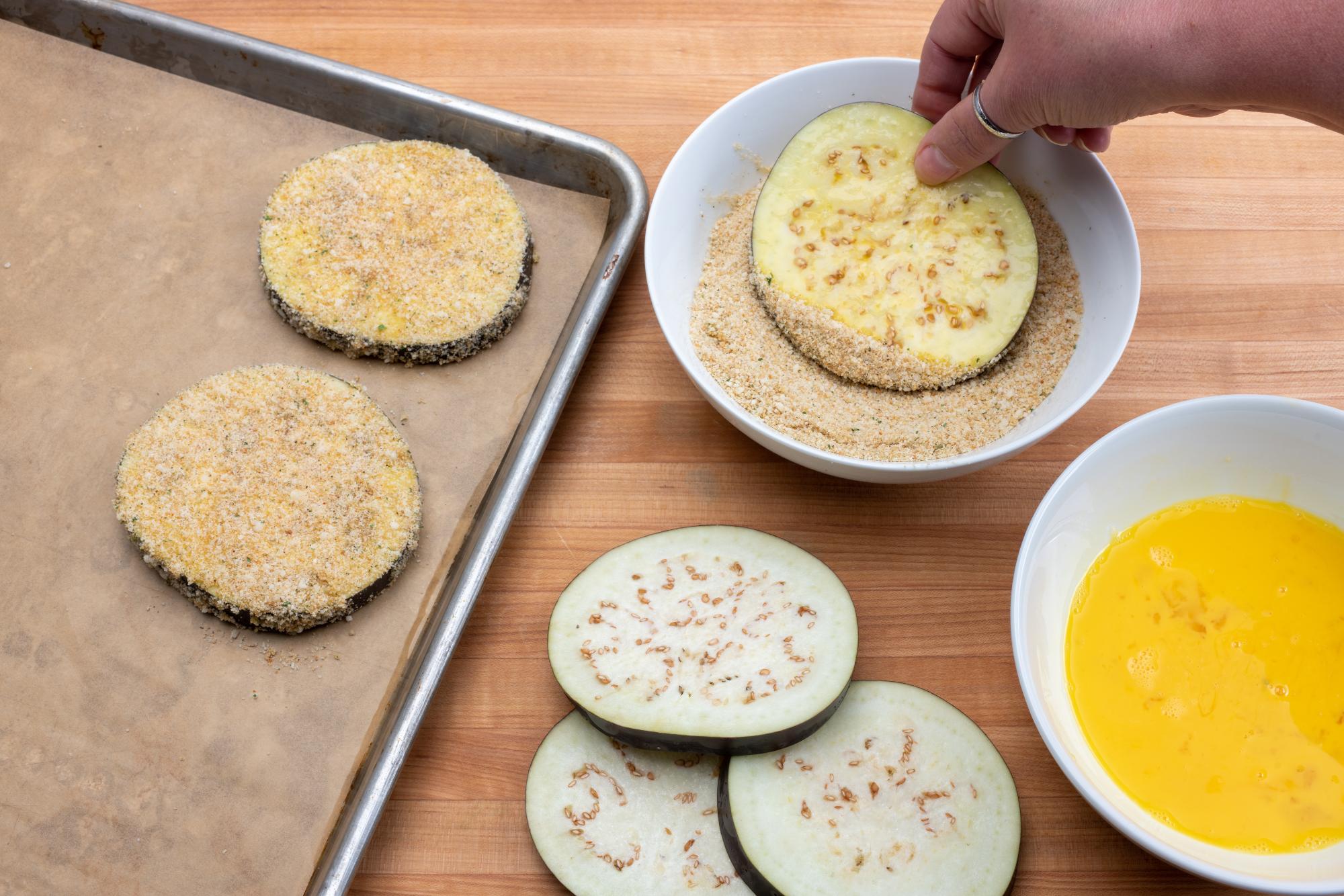 Coating the slices in the seasoned breadcrumb mixture.