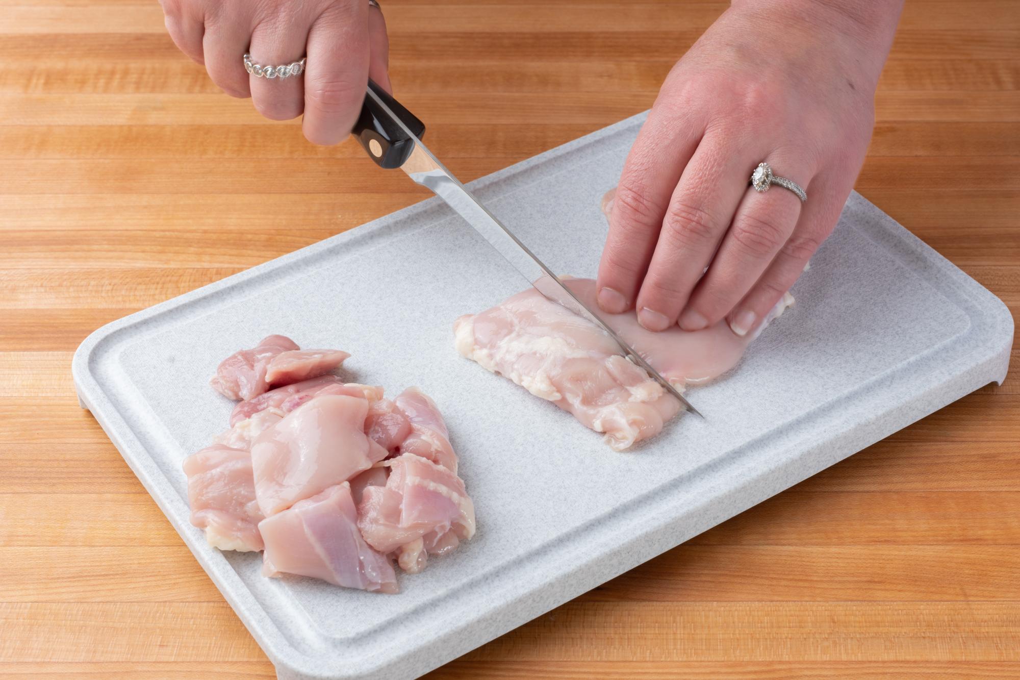 Cutting the chicken into pieces with a Boning Knife.