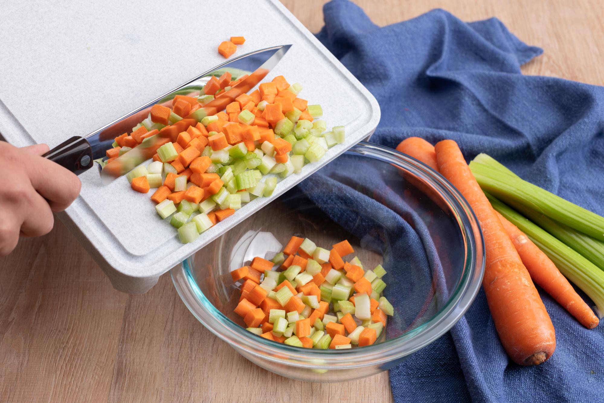 Scraping food with the sharp edge of a knife.