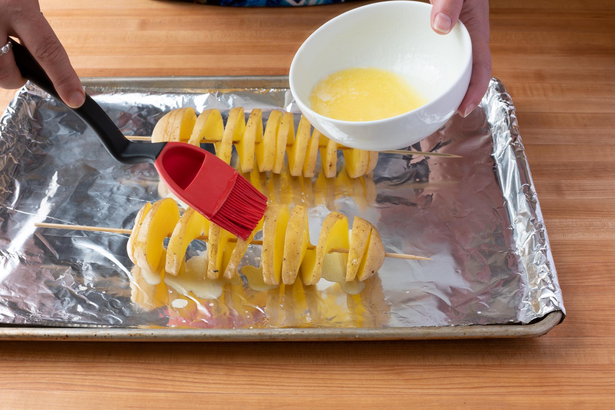 Brushing the potato with butter.