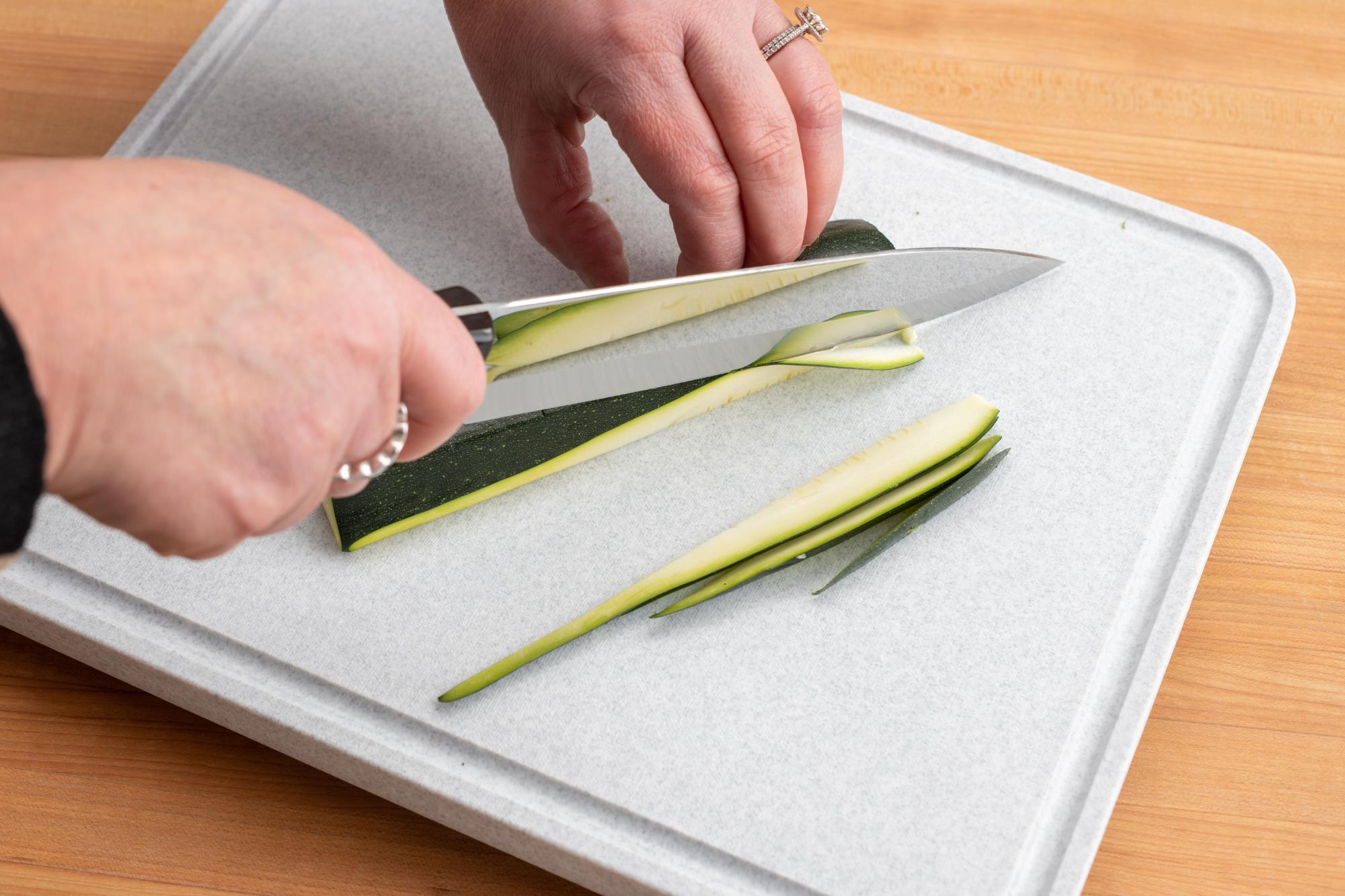 Cutting zucchini into thin strips.