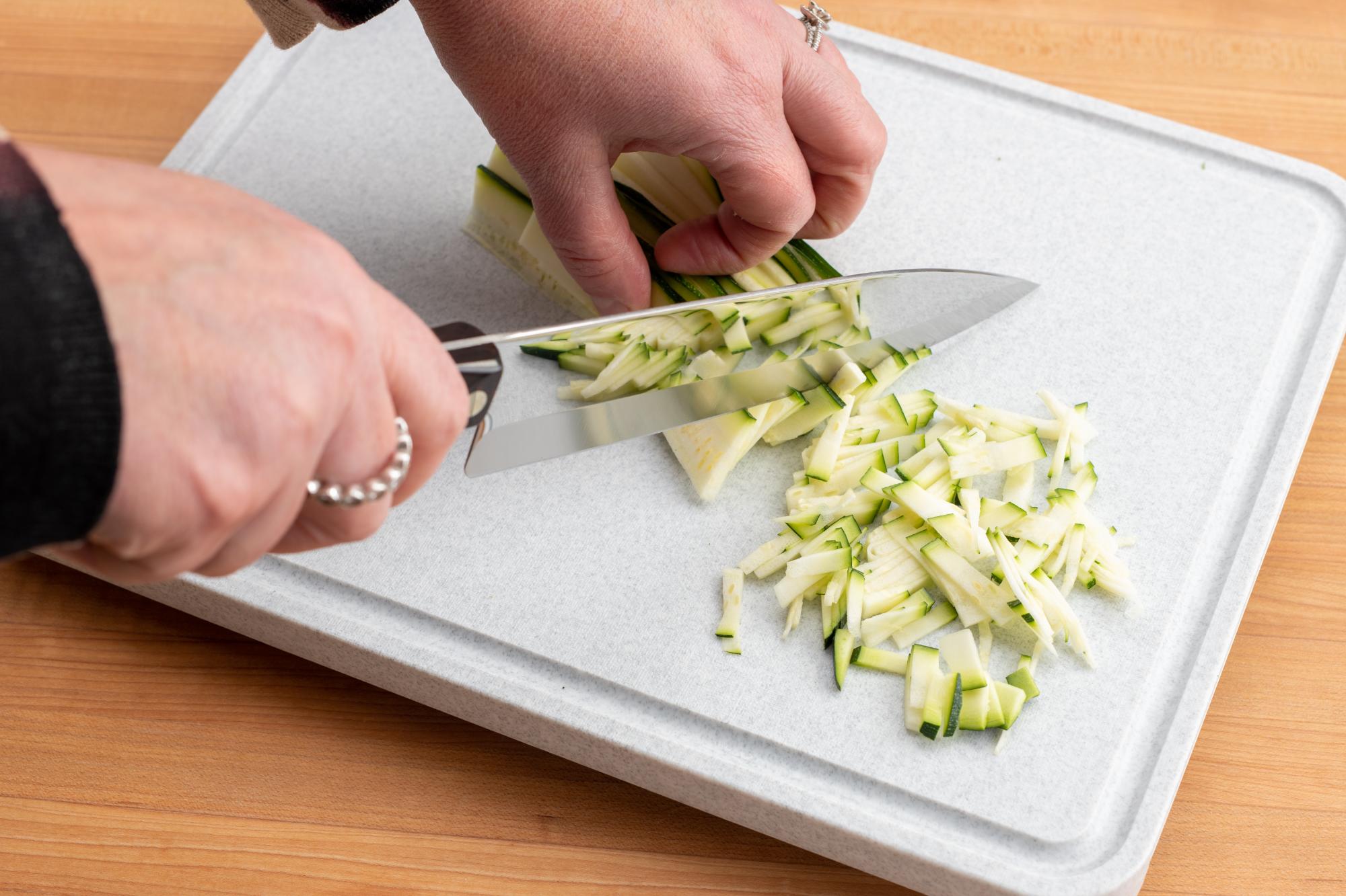 Cutting the zucchini strips, crosswise.