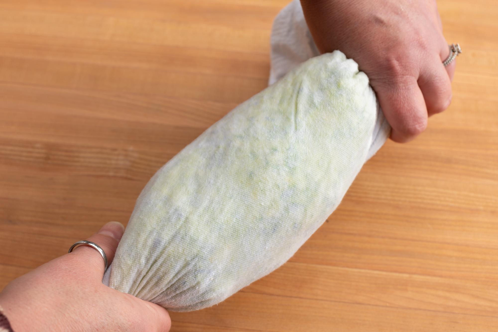 Using a towel to wring moisture from the zucchini.