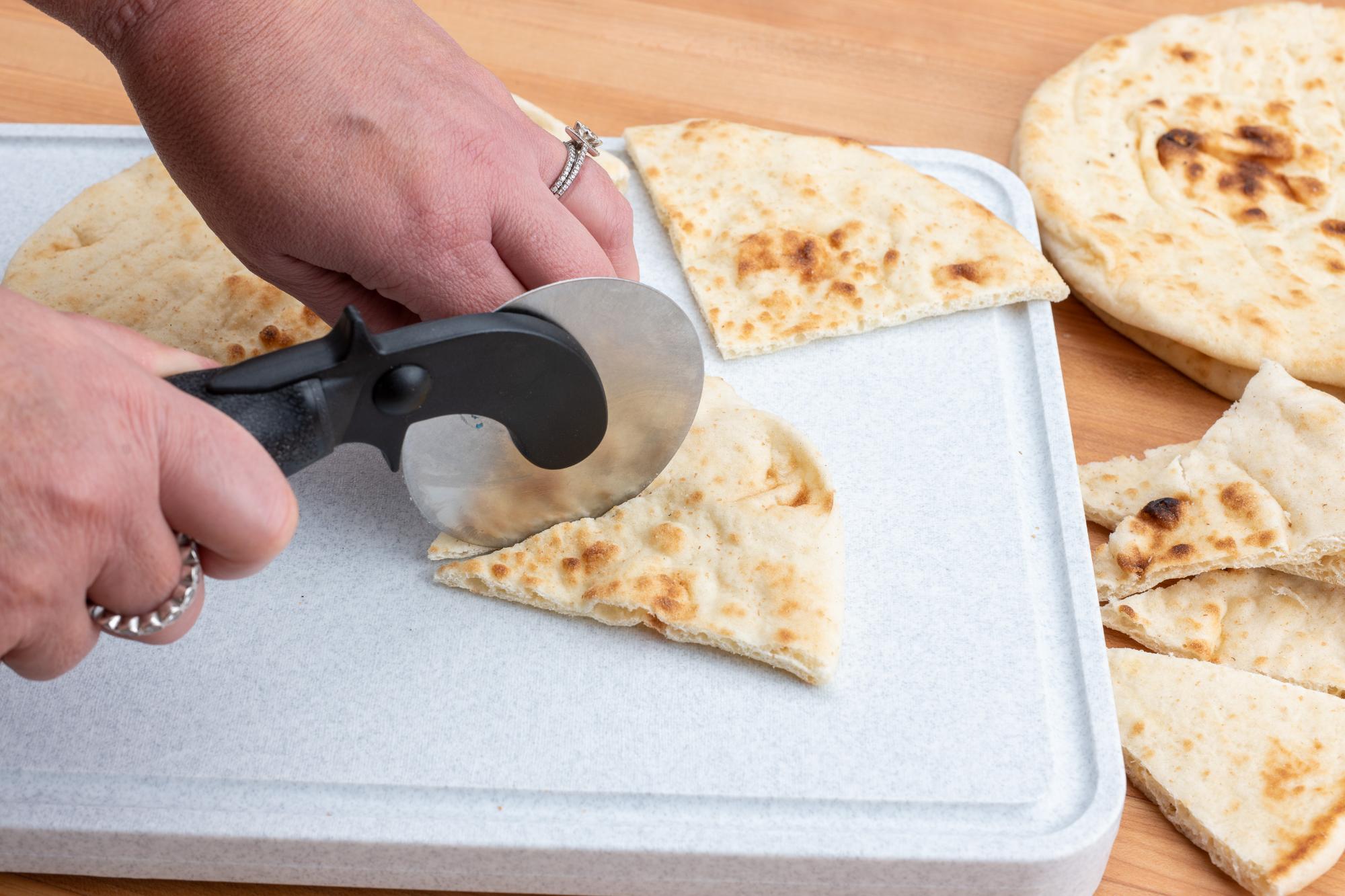 Cutting pita with a pizza cutter.