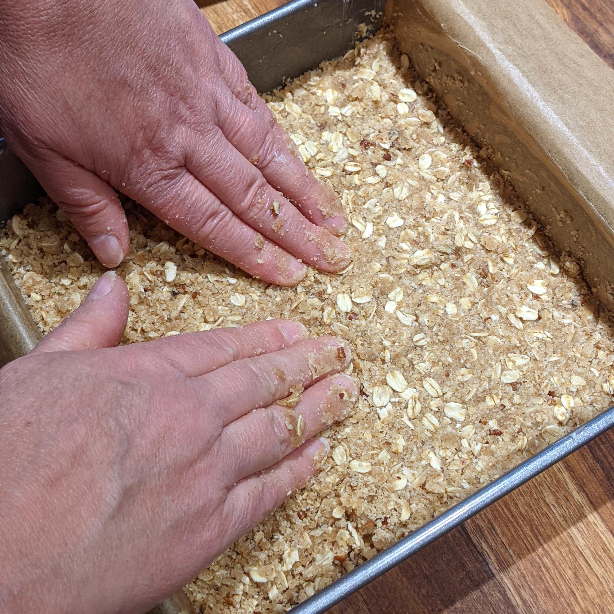 Pressing the crumb mixture into the pan.
