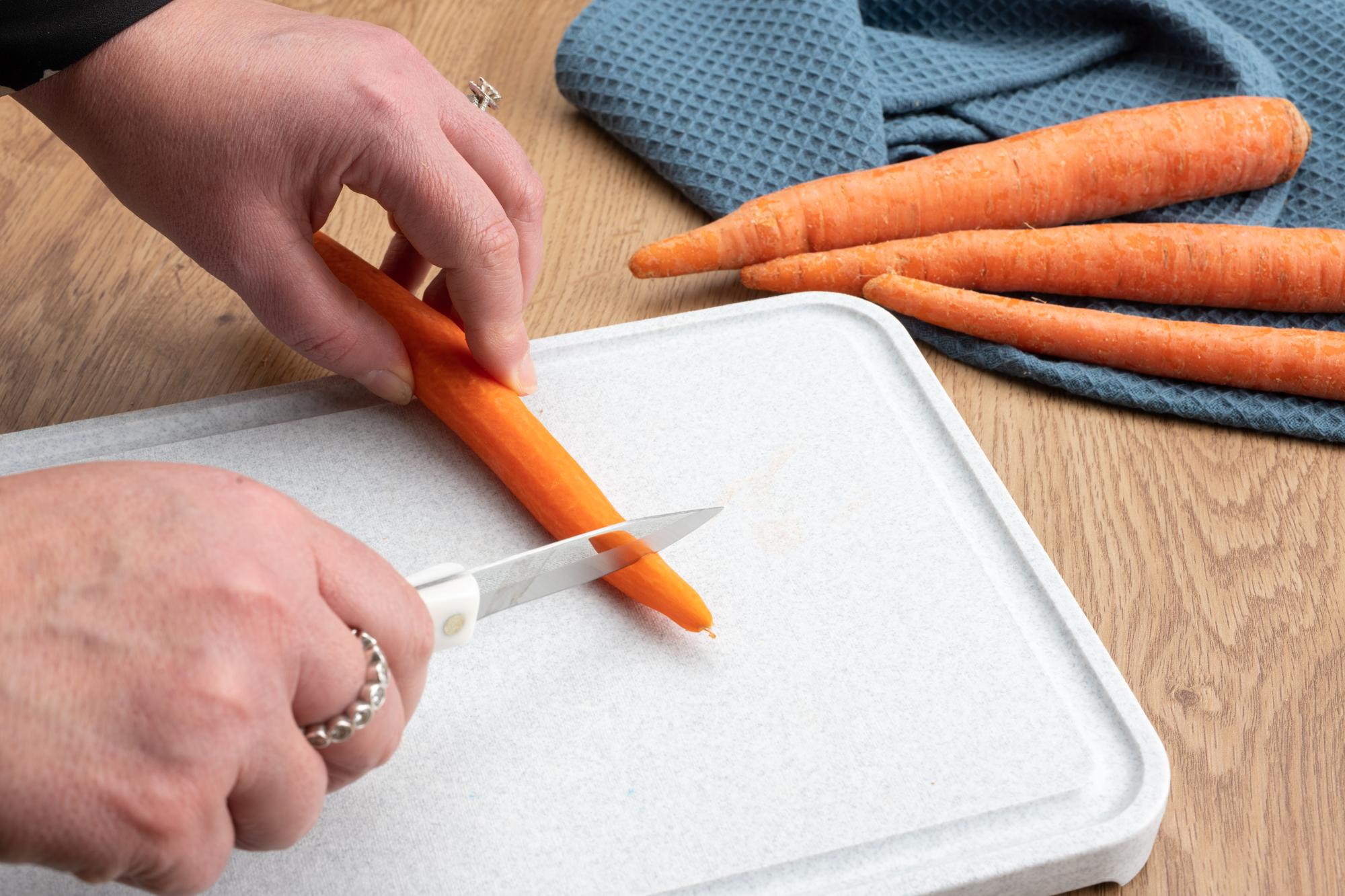 Trimming the tip off the carrot with a Paring Knife.