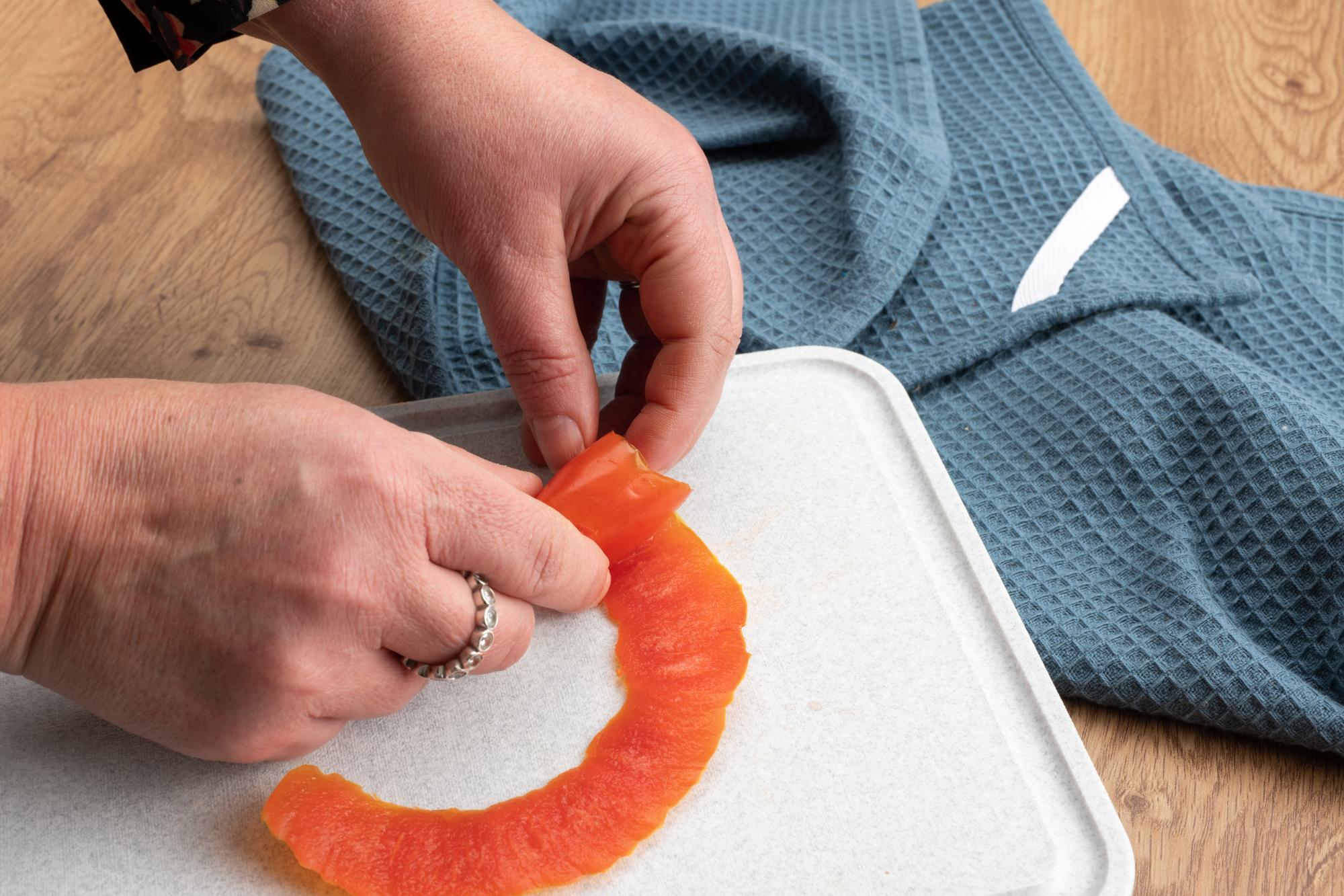 Rolling the tomato peel up into a rose shape.