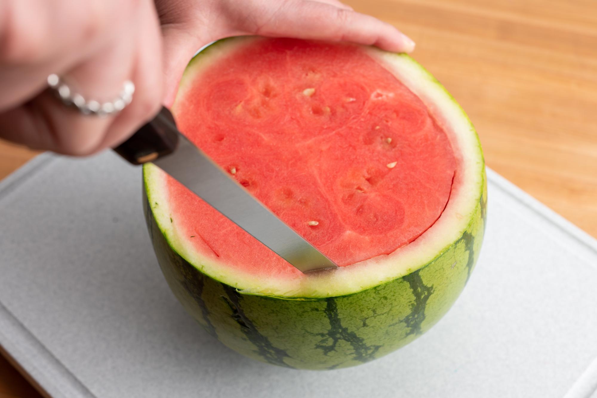 Using a Salmon knife to cut around the inside of the watermelon.