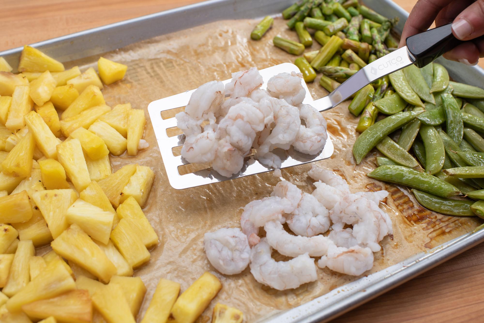 Placing shrimp on the pan with a Slotted Turner.