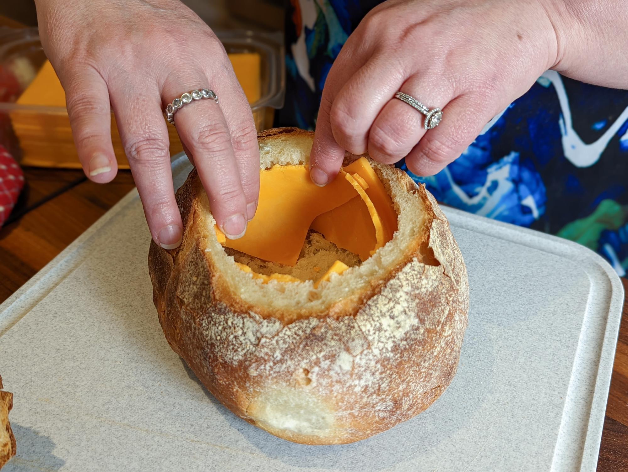Lining the bread bowl with cheese.