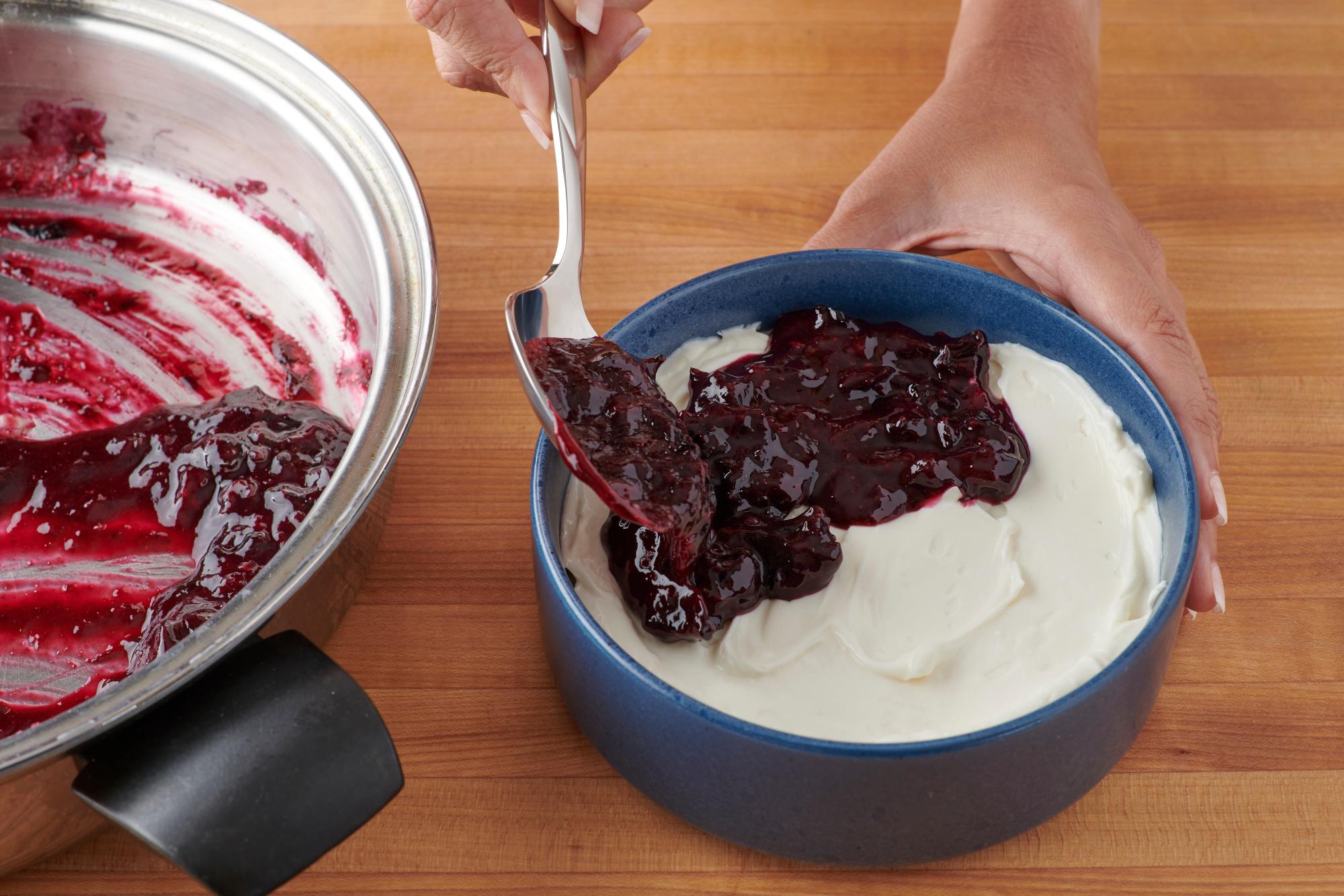 Spooning the mashed blueberries over the cream cheese mixture.