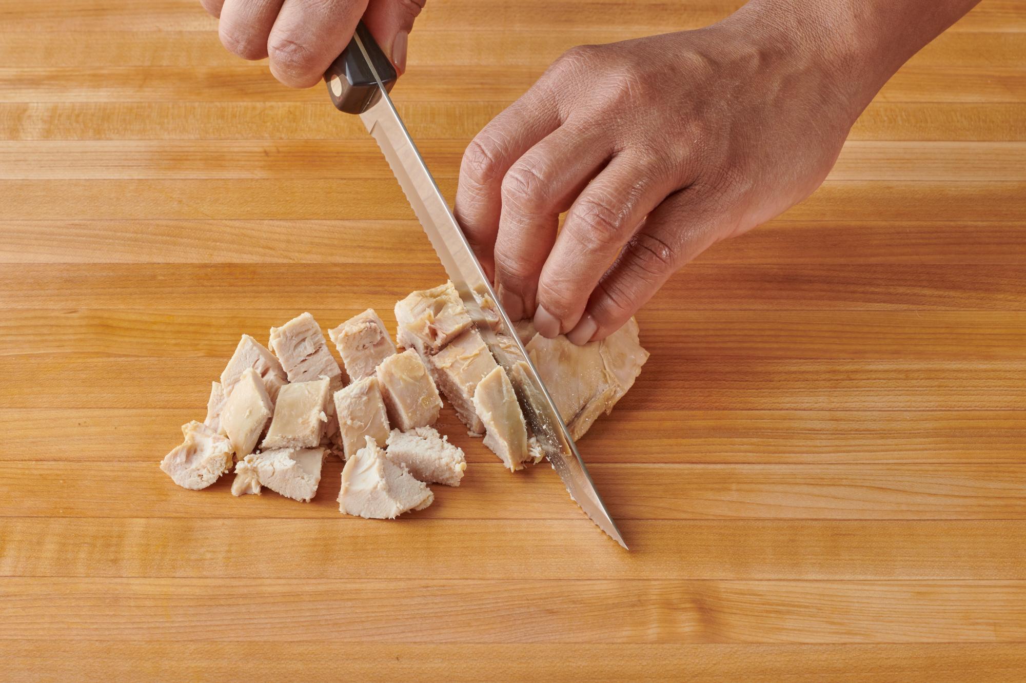 Using a Petite Carver to cut the chicken into cubes.