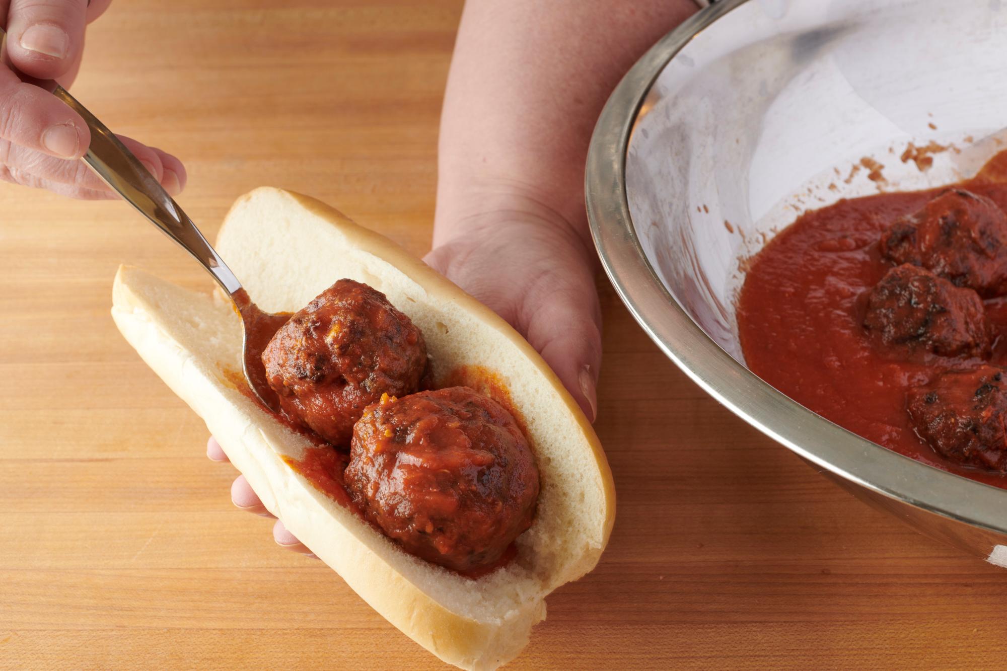 Placing meatballs on the rolls.