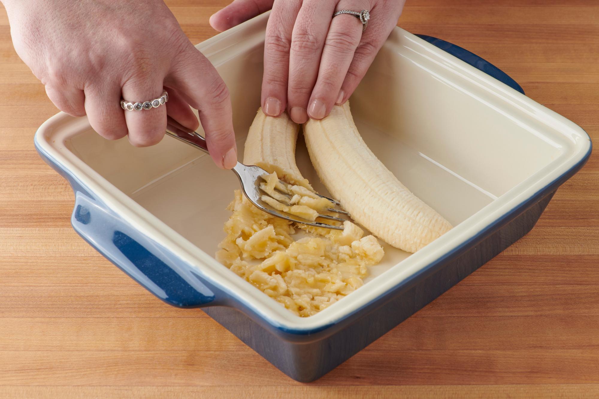 Mashing the banana into the pan.