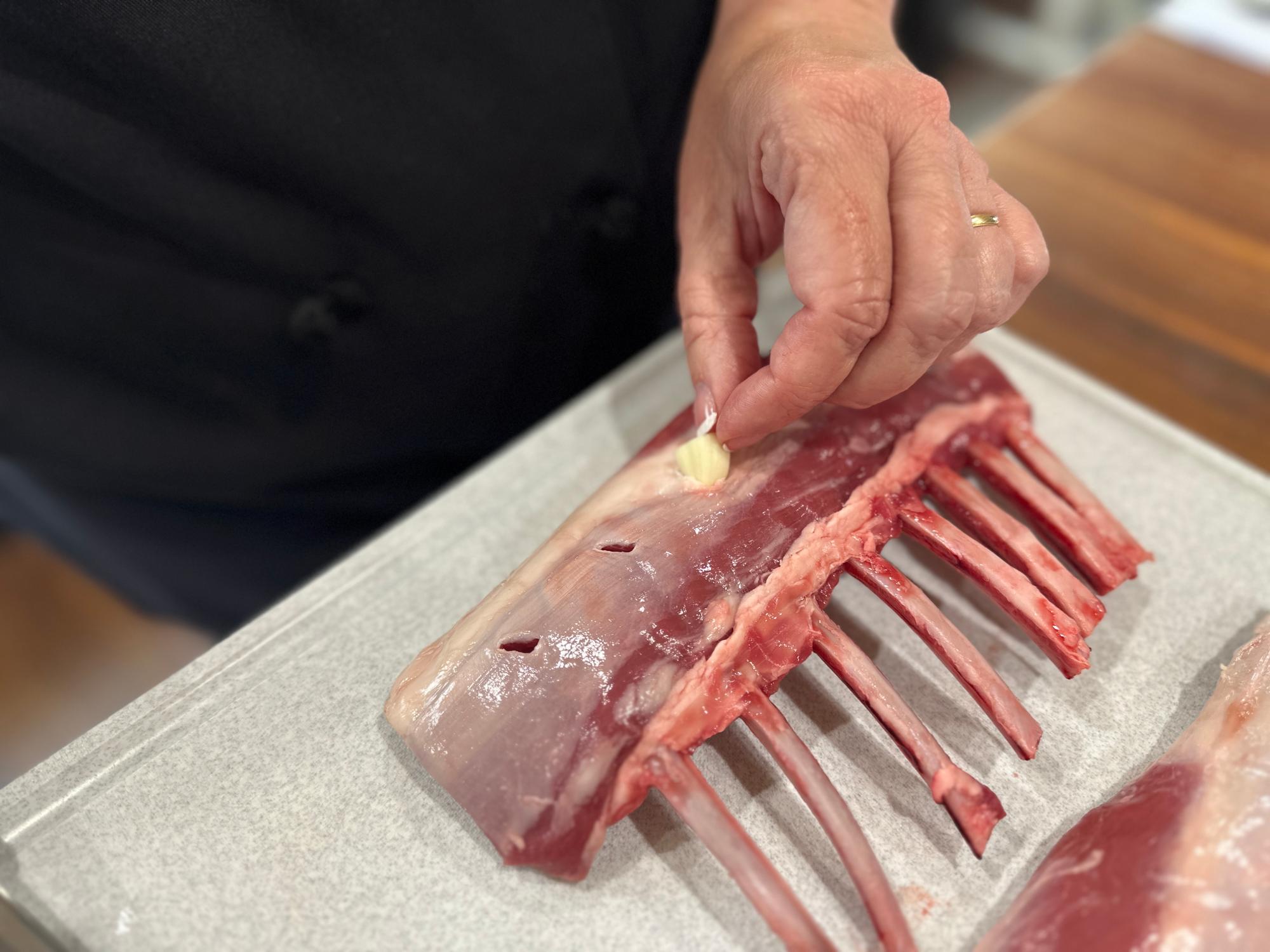 Inserting the garlic into the rack of lamb.