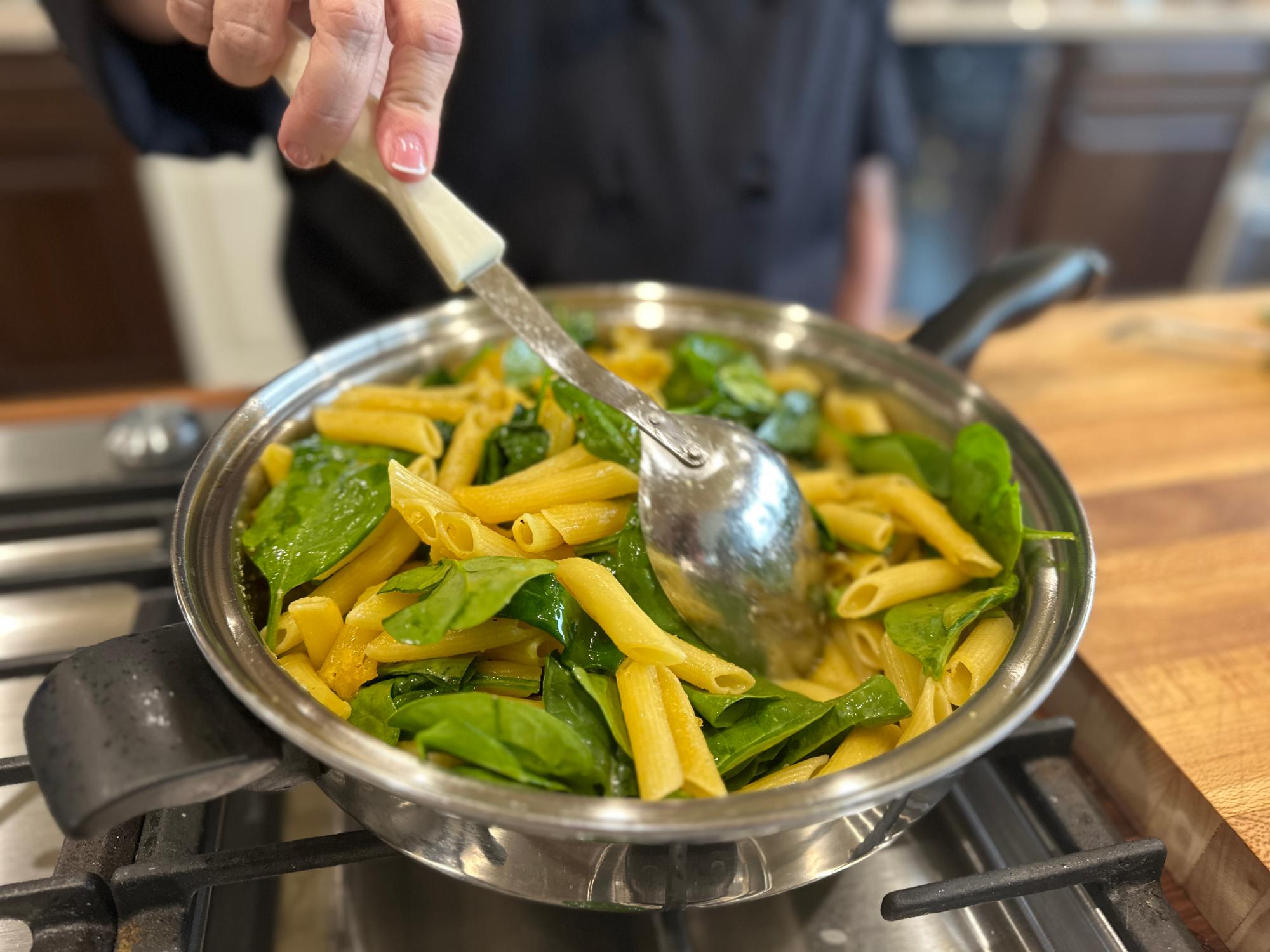 Adding spinach to the pan.