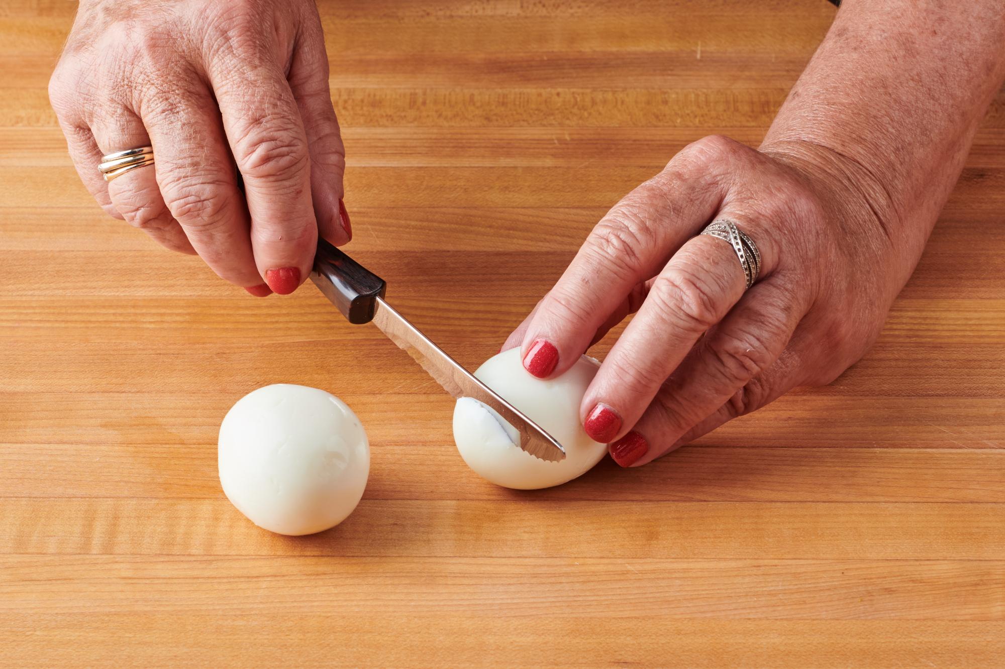 Trimming off small slice from bottom of egg with Table Knife