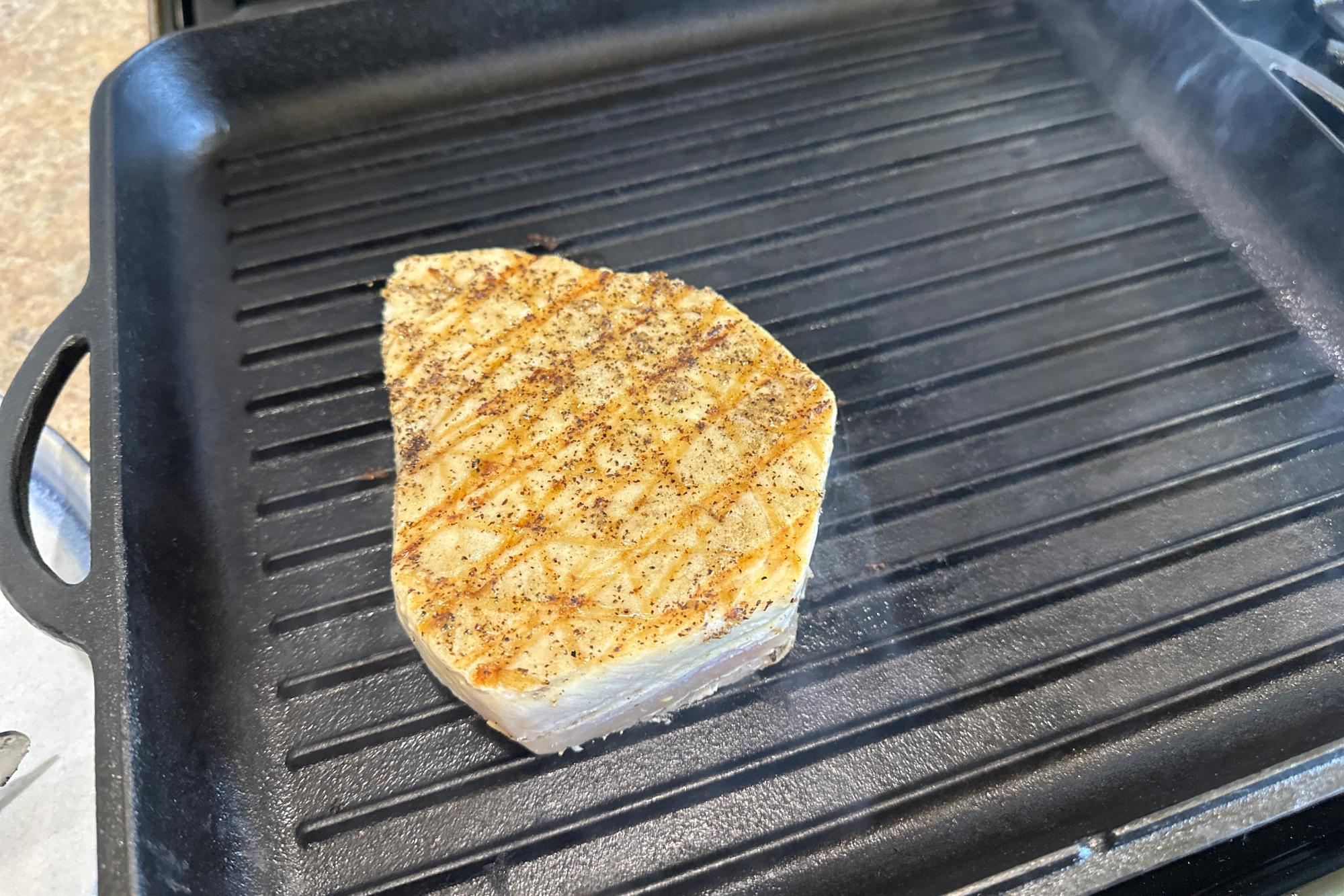 Swordfish grilling in pan.