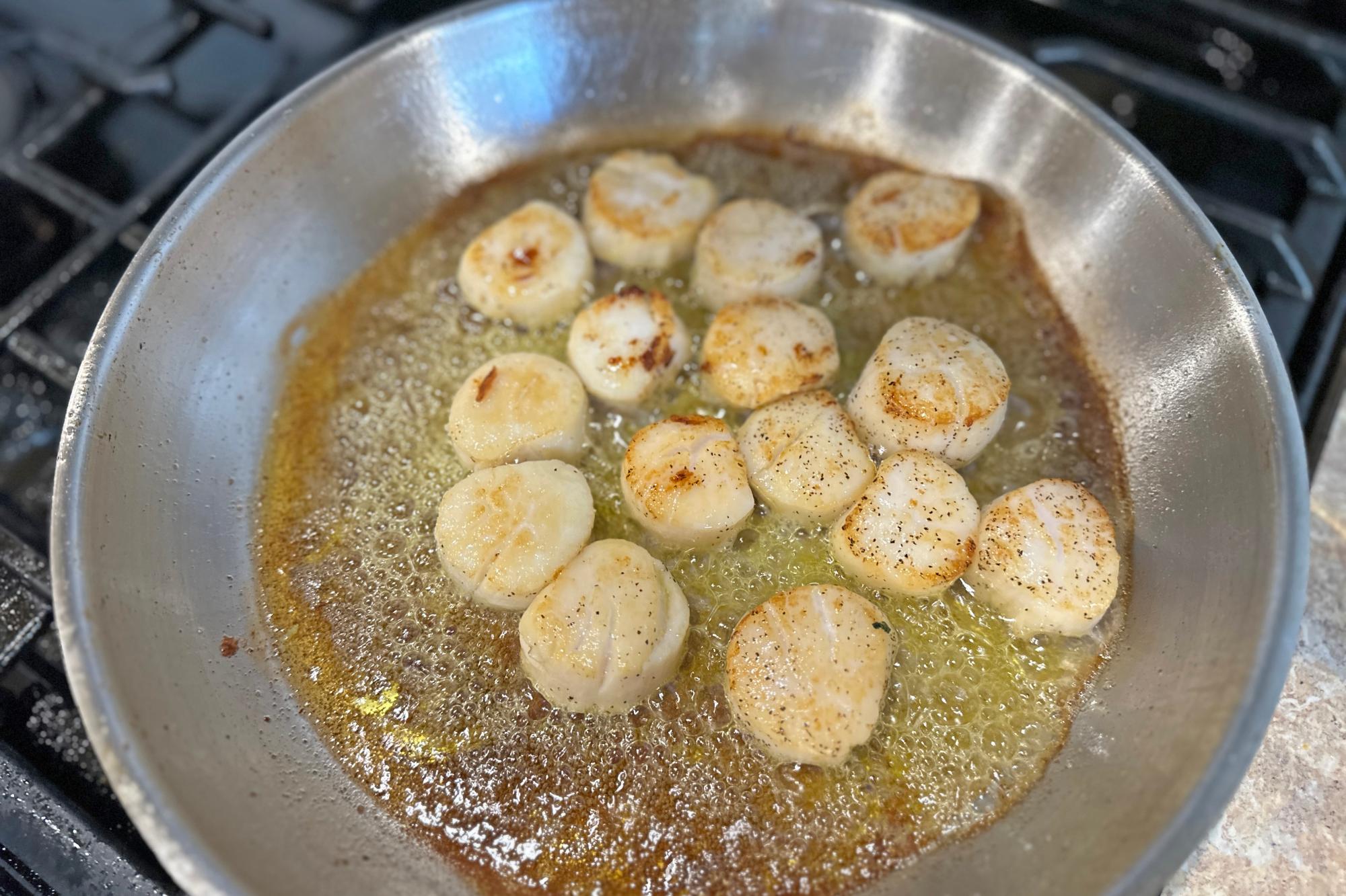 Browning scallops in a pan.