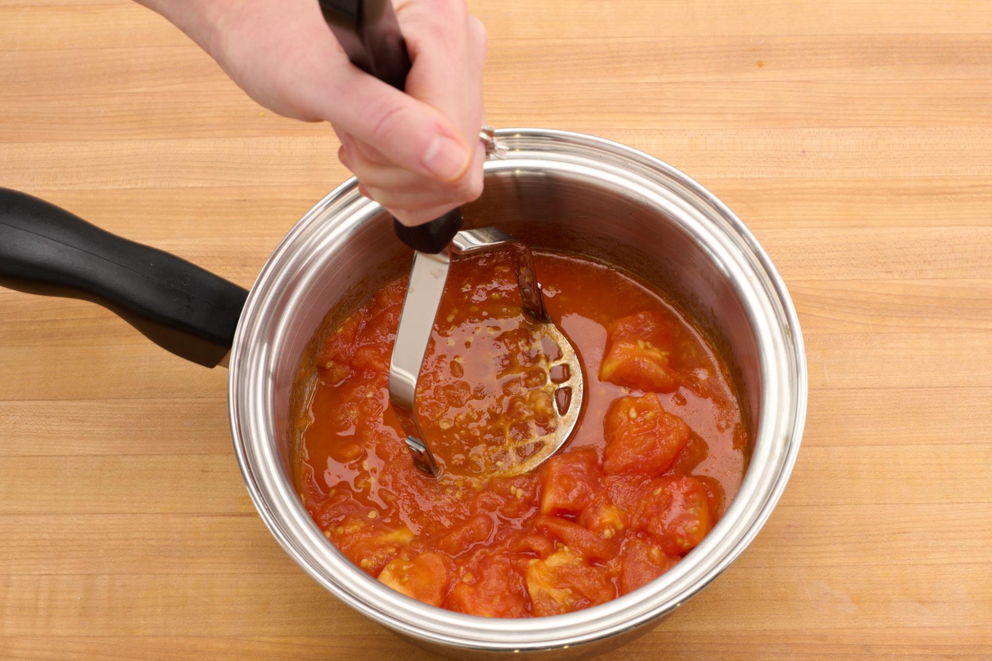 mashing cooked tomatoes