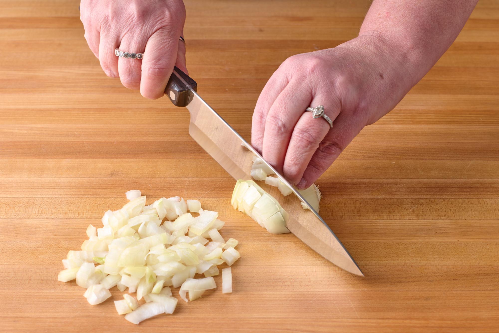 Rough chopping a yellow onion with a 7-5/8 Inch Petite Chef knife.