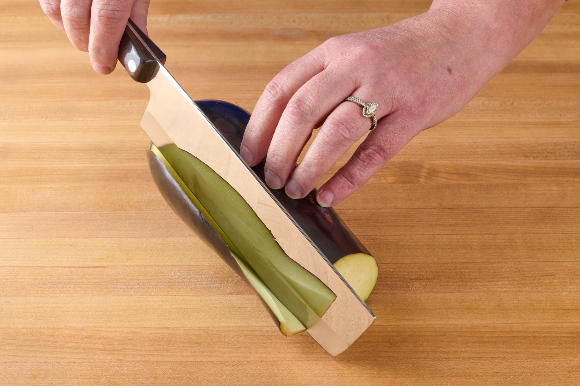 Cutting thin slice off eggplant with a Vegetable Knife.