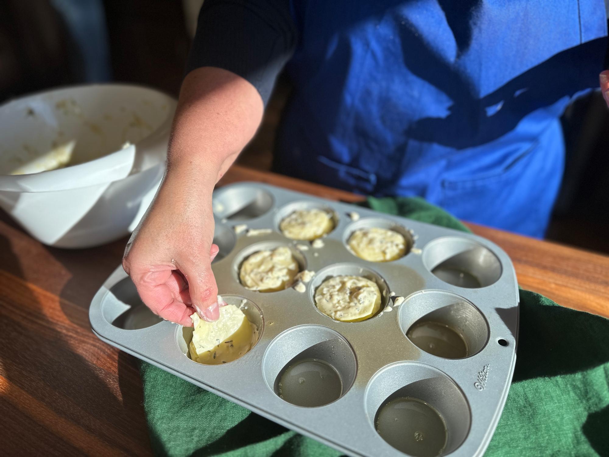 Layer the potato slices into the prepared muffin cups