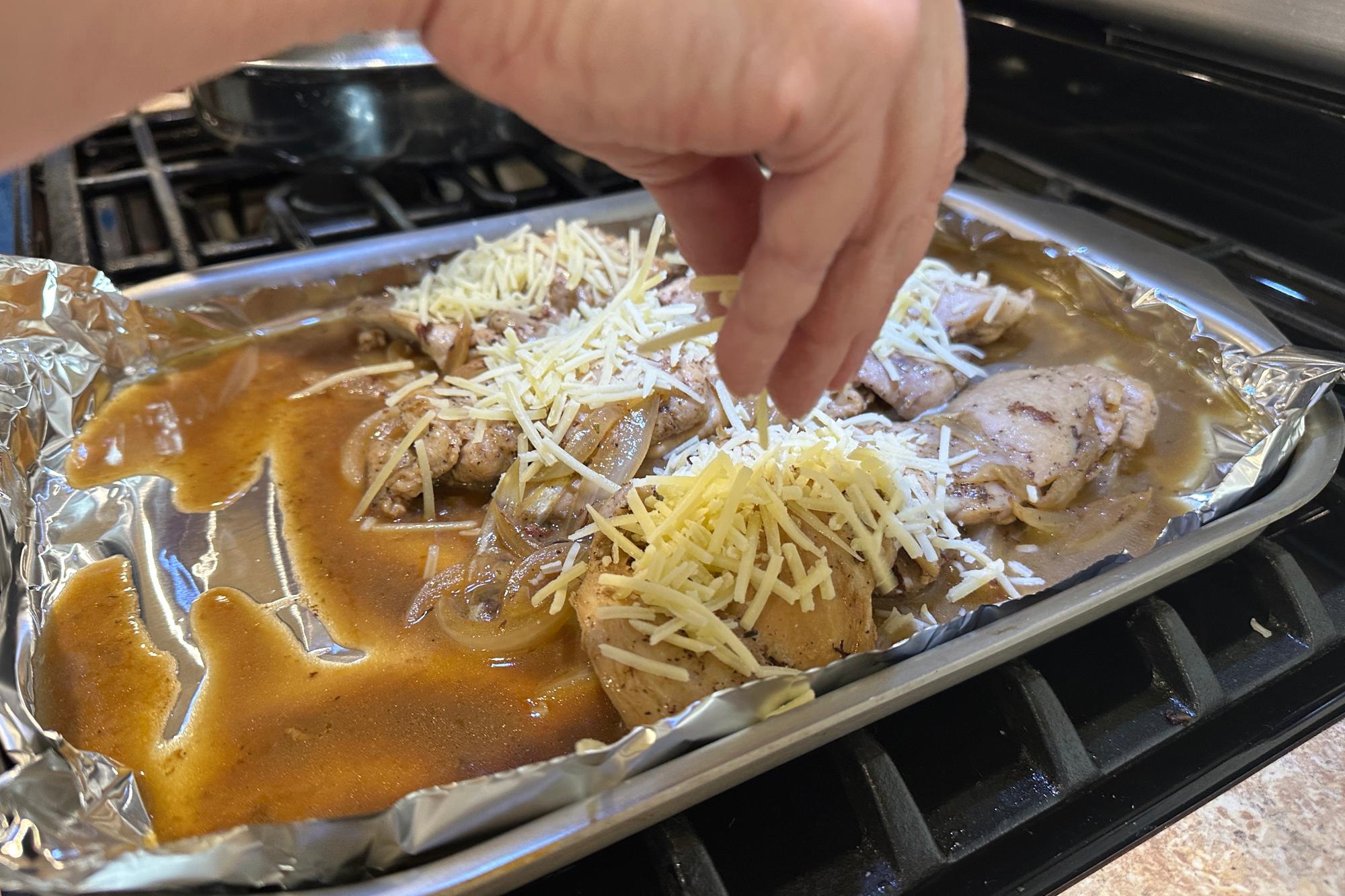 Placing Gruyere cheese on chicken before broiling.