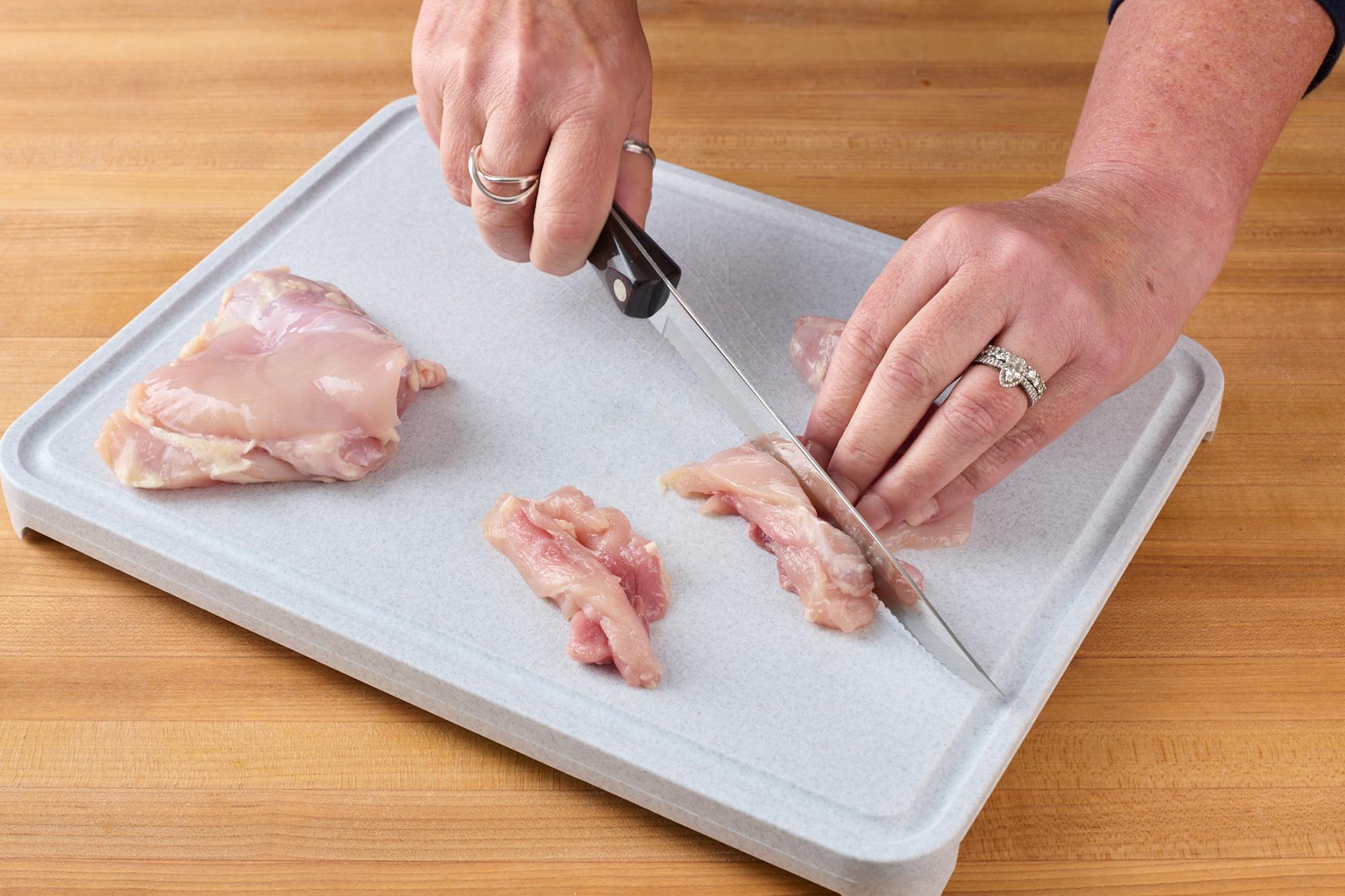 Cutting chicken thighs into strips