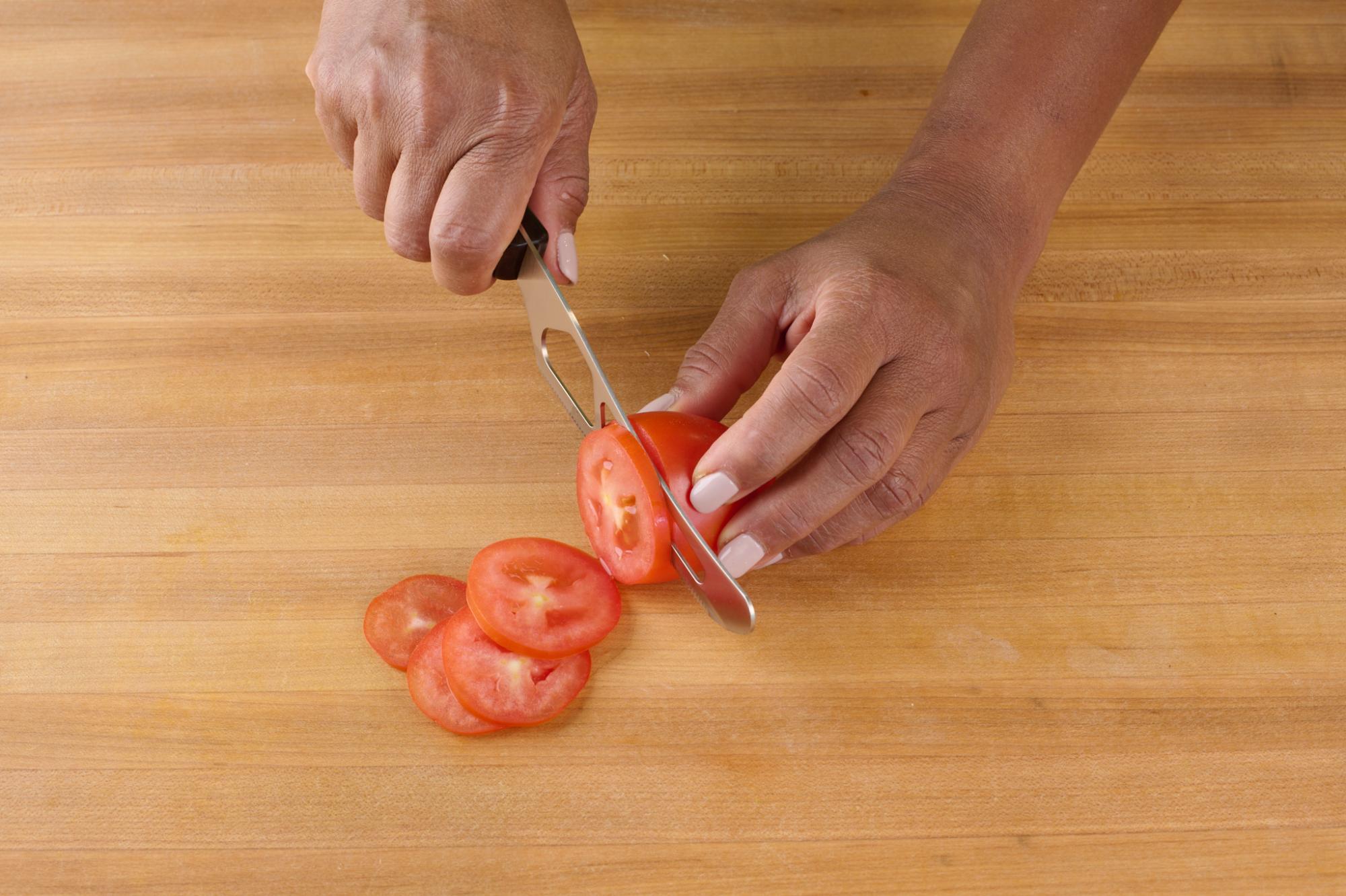 Slicing plum tomato with Traditional Cheese Knife.
