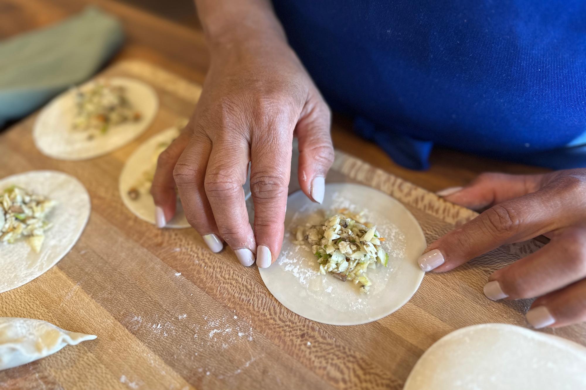 Wetting the edges of dumpling wrapper with water using finger.