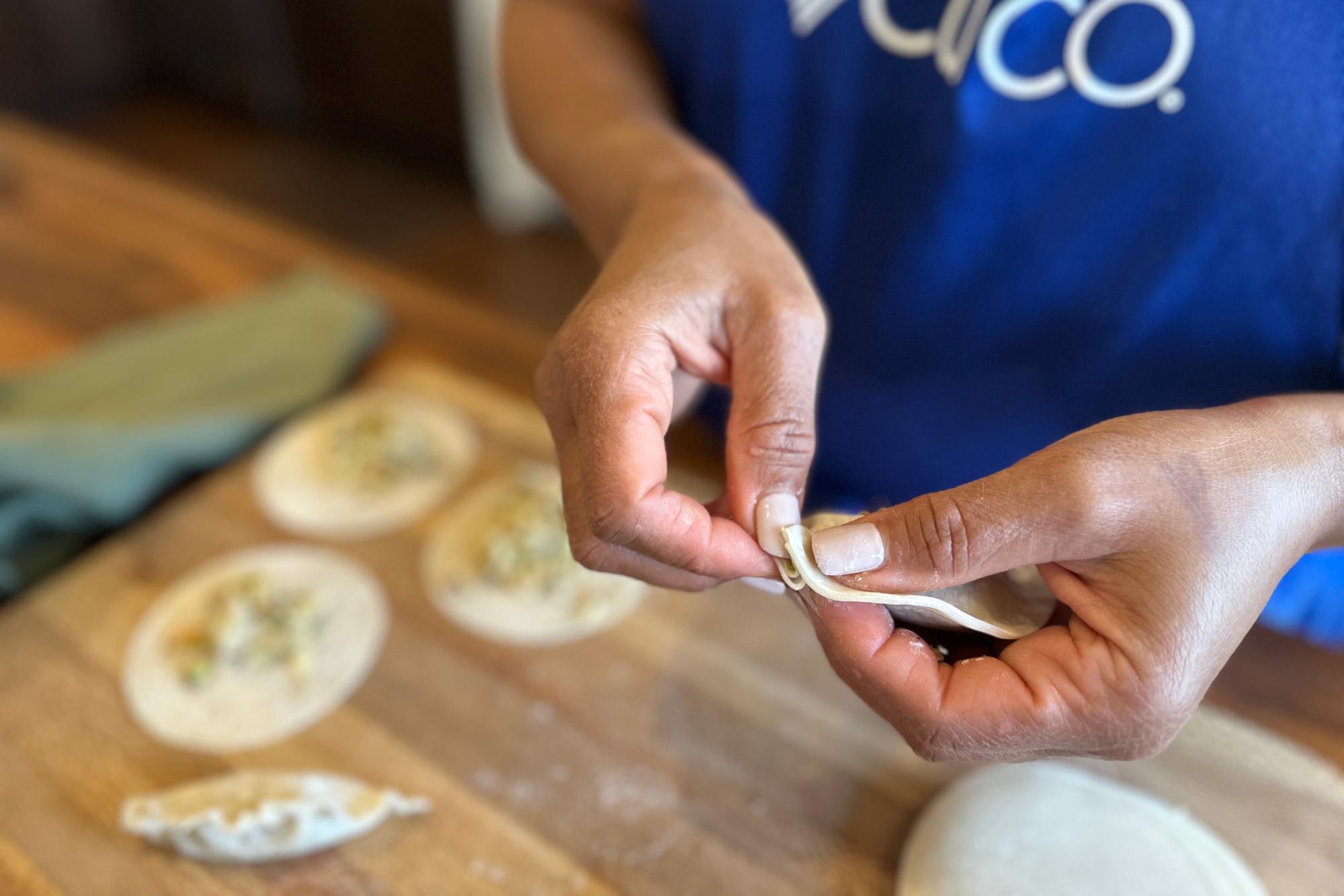 Wetting the edges of dumpling wrapper with water using finger.