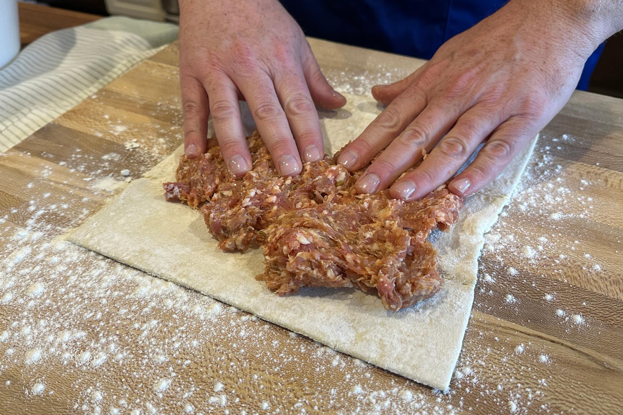 Placing sausage on pastry.