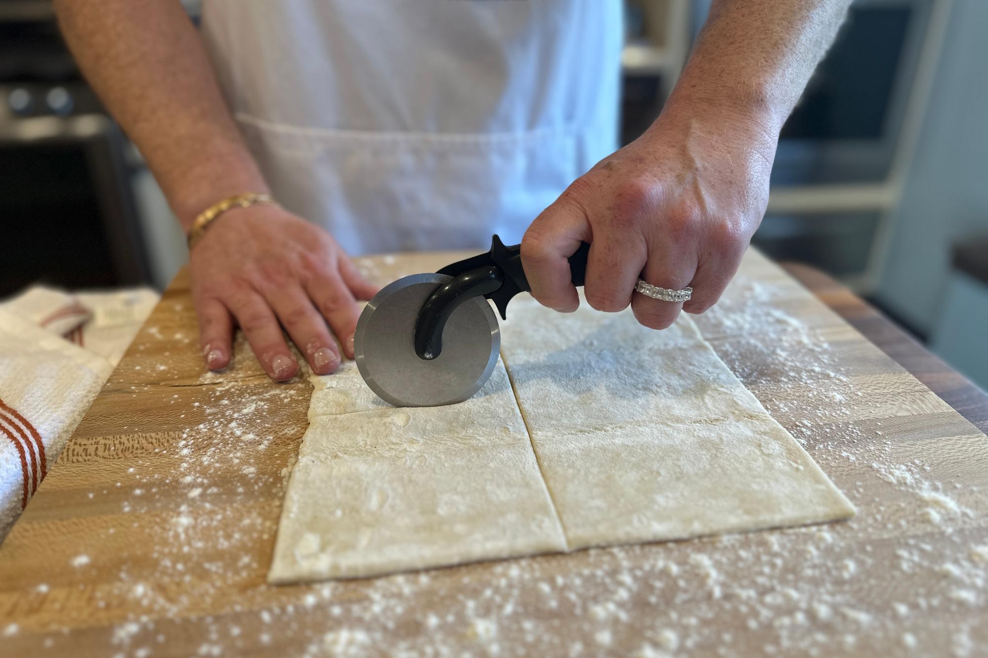 Dividing puff pastry into four squares with Pizza Cutter.