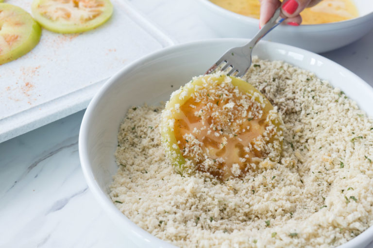 Dipping the tomato in the breadcrumb mixture.