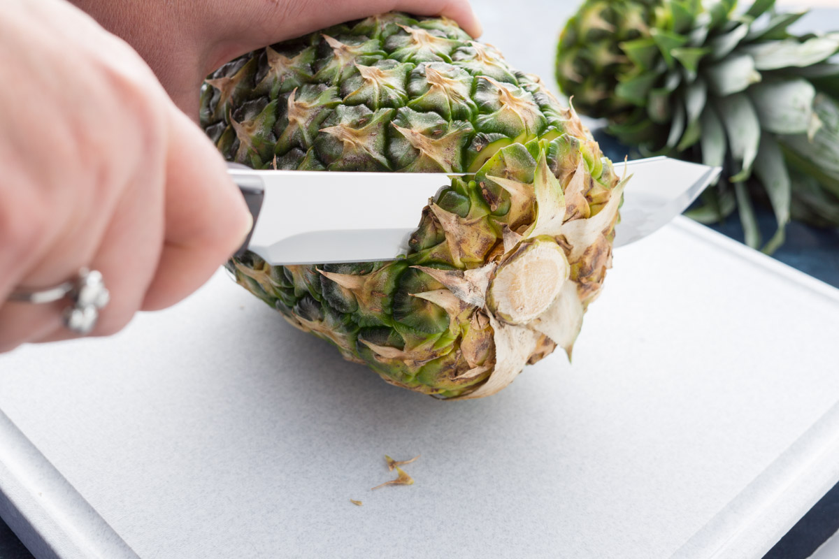 Cutting the bottom off the pineapple with a Butcher Knife.